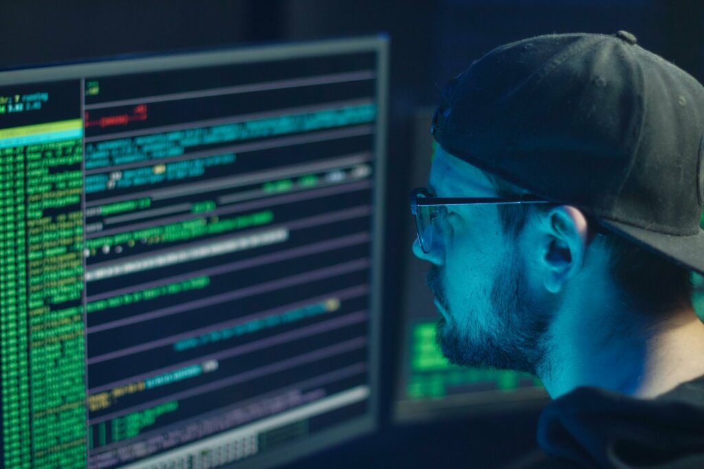 Un analyste en cybersécurité travaillant sur du code affiché sur un écran, illustrant la surveillance et la protection contre les cyberattaques