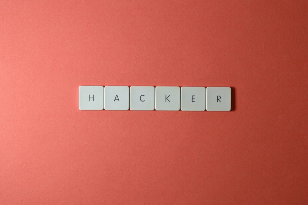 Le mot 'HACKER' écrit avec des touches de clavier sur un fond rouge, symbolisant la cybersécurité et les menaces informatiques