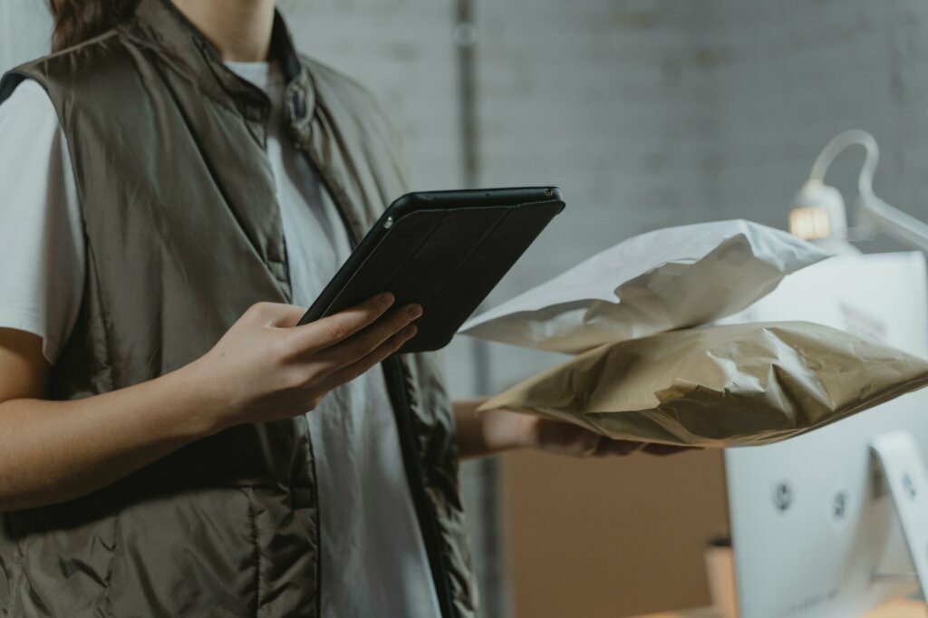 Employé en logistique scannant des colis avec une tablette dans un entrepôt industriel