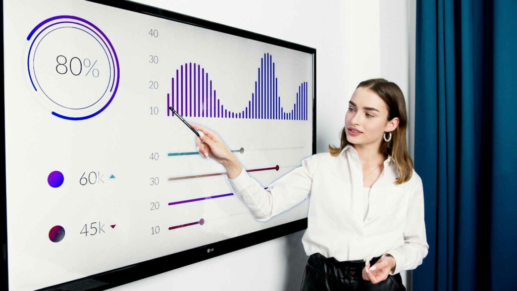 Collaboratrice présentant des indicateurs visuels sur un écran pour appuyer la prise de décision stratégique en entreprise