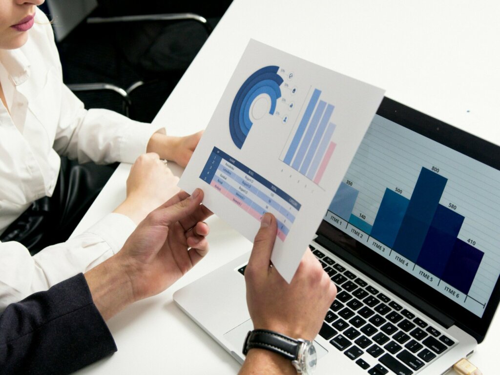 Analyse d’indicateurs commerciaux avec un tableau de bord sur ordinateur et un graphique papier, illustrant le pilotage de la performance grâce à un CRM