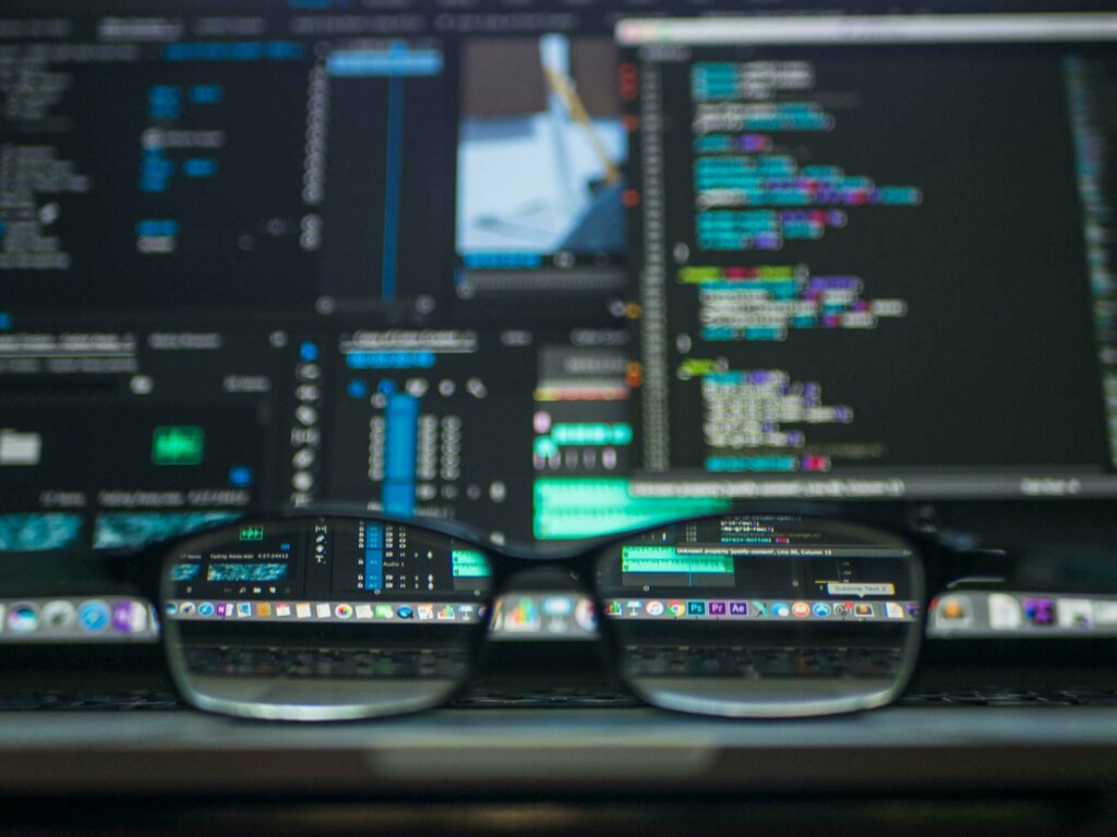 Écran affichant du code informatique reflété dans une paire de lunettes, illustrant la sécurité et la surveillance des données